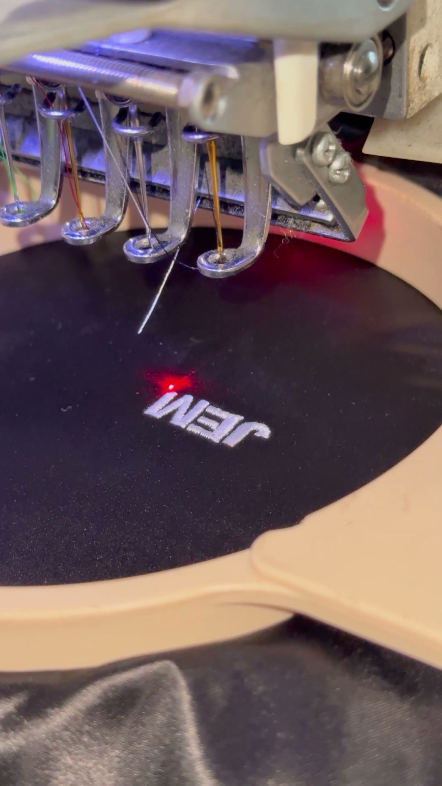 Close-up of an embroidery hoop with fresh stitching on dark fabric at a live station